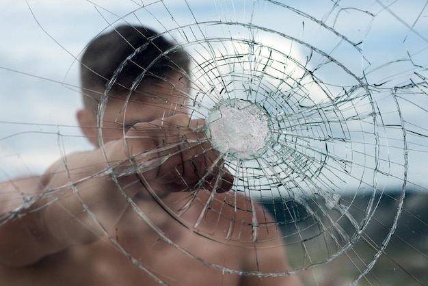 Vuiststoot Klaar om te vechten Man boksen gebarsten glas kracht en macht Criminele man met serieus gezicht