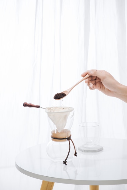 Vul gemalen koffie in filter met houten lepel