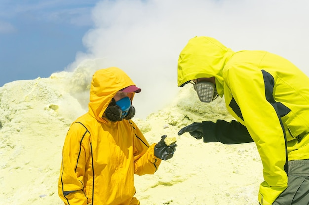 Vulkanologen op de helling van de vulkaan onderzoeken monsters van mineralen tegen de achtergrond van rokende zwavelfumarolen