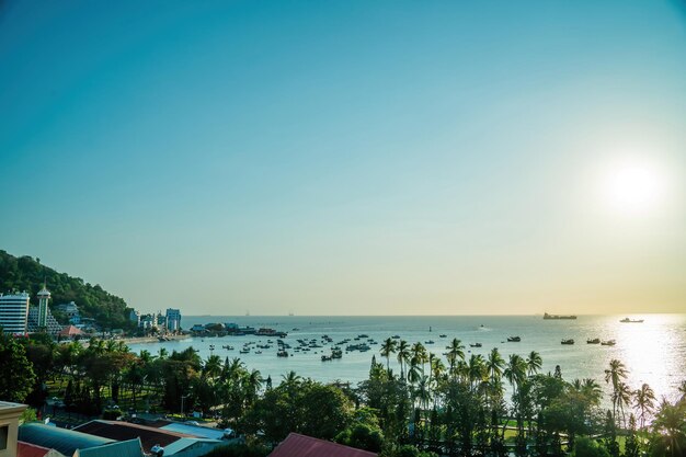 Vung Tau city aerial view with beautiful sunset and so many boats Panoramic coastal Vung Tau view from above with waves coastline streets coconut trees and Tao Phung mountain in Vietnam