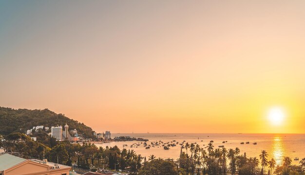 美しい夕日とたくさんのボートがあるブンタウ市の空中写真波の海岸線の通りココナッツの木とベトナムのタオプン山のある上からのパノラマ沿岸ブンタウビュー