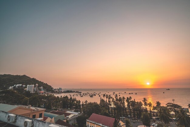 아름다운 일몰과 많은 보트가 있는 붕따우 도시 공중 전망 파도가 치는 해안선 거리 코코넛 나무와 베트남 타오풍 산이 있는 탁 트인 해안 붕따우 전망