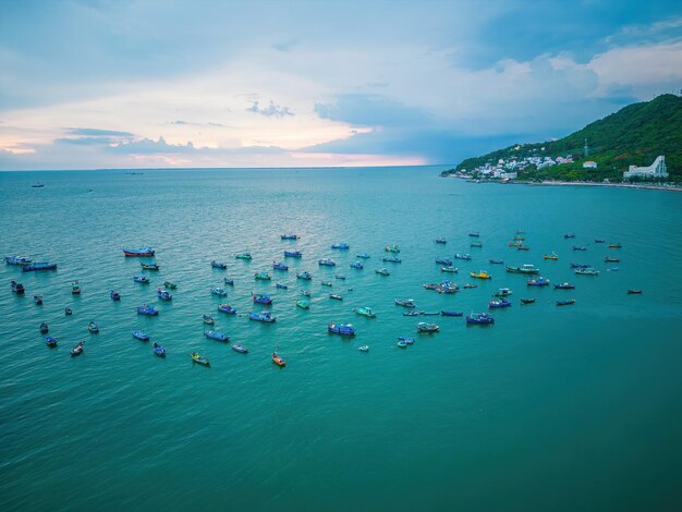 Vung Tau city aerial view with beautiful sunset and so many boats Panoramic coastal Vung Tau view from above with waves coastline streets coconut trees and Tao Phung mountain in Vietnam