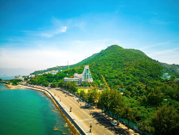 Vung Tau city aerial view with beautiful sunset and so many boats Panoramic coastal Vung Tau view from above with waves coastline streets coconut trees and Tao Phung mountain in Vietnam