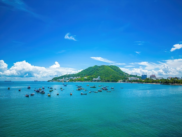 Vung Tau city aerial view with beautiful sunset and so many boats Panoramic coastal Vung Tau view from above with waves coastline streets coconut trees and Tao Phung mountain in Vietnam