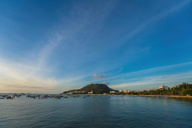 美しい夕日とたくさんのボートがあるブンタウ市の空中写真波の海岸線の通りココナッツの木とベトナムのタオプン山のある上からのパノラマ沿岸ブンタウビュー