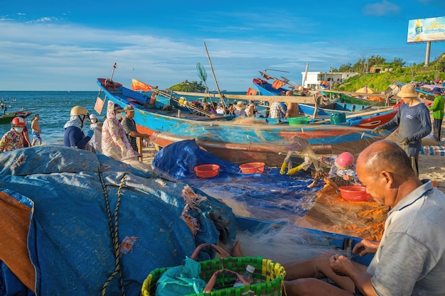 Vung Tau VIETNAM 20 AUGUSTUS 2022 Visser werpt zijn net uit bij zonsopgang of zonsondergang Traditionele vissers bereiden het visnet voor Vissers op het strand bij de Visserij