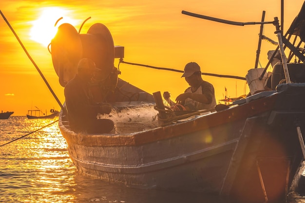 Vung tau vietnam mar 25 2023 fisherman casting his net on the boat at the sunrise or sunset traditional fishermen prepare the fishing net