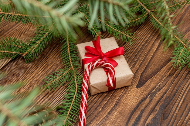 Vuren vuren naaldhout takken, geschenkdoos ambachtelijke papier met rode strik op de bruin geborsteld houten tafel