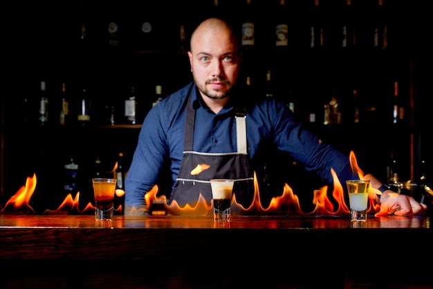 Vurige show aan de bar. De barman maakt een hete alcoholische cocktail en ontsteekt een reep. Barman bereidt een vurige cocktail. Vuur op bar.