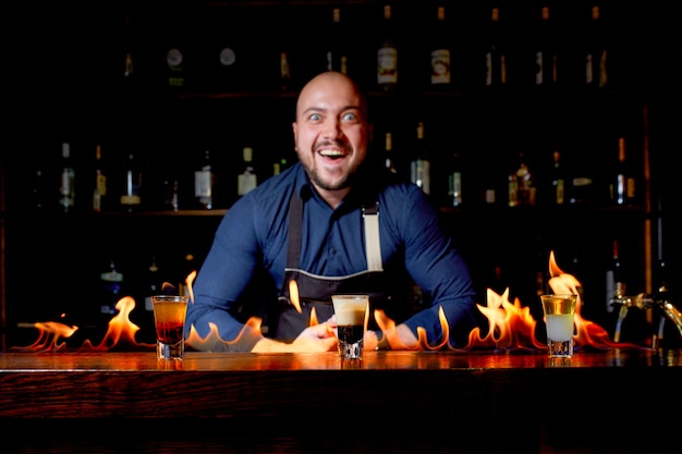 Vurige show aan de bar. De barman maakt een hete alcoholische cocktail en steekt de bar aan. Barman bereidt een vurige cocktail. Vuur op bar.