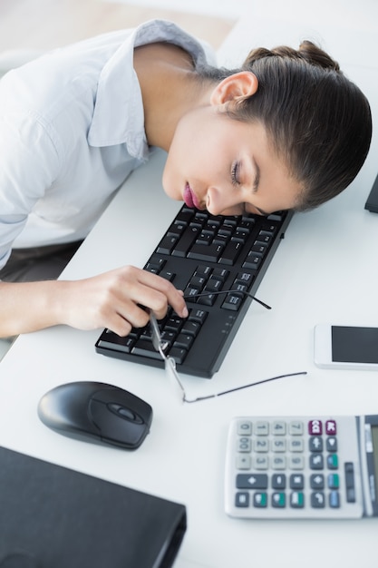 Vusinesswoman resting head on keyboard in office