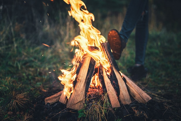 Vuur in het bos met meisje die erachter opwarmen.