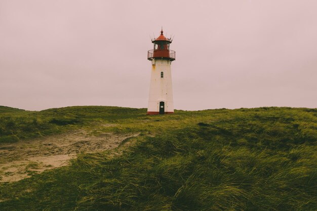 Vuurtoren door de zee tegen de lucht