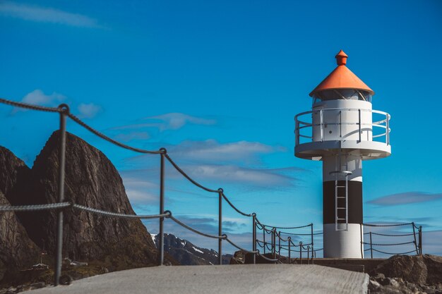 Vuurtoren op de pier op de achtergrond van de bergen en de blauwe lucht op de Lofoten-eilanden.