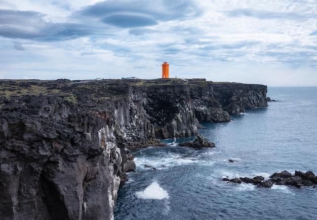 Vuurtoren op de rotsen in IJsland Hoge rotsen en vuurtoren overdag Natuurlijk landschap in de zomer IJsland afbeelding