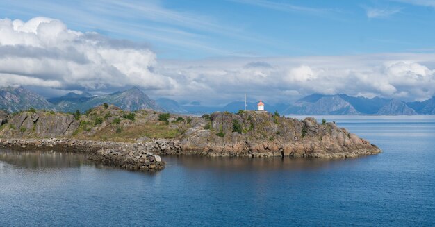 Vuurtoren op een rotsachtige kaap op een achtergrond van bergen, Lofoten-archipel, Noorwegen