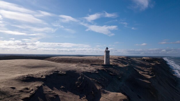 Foto vuurtoren op het strand bij de zee tegen de lucht