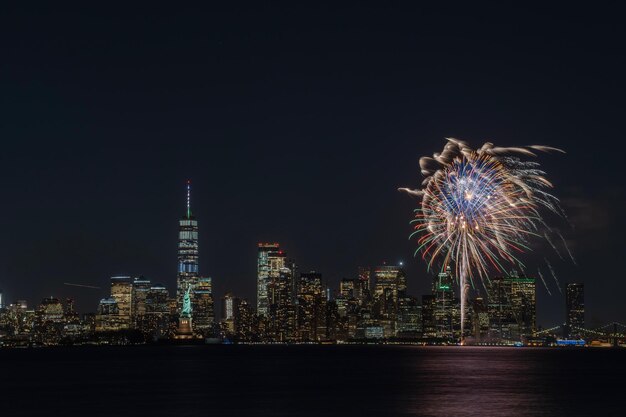 Vuurwerk boven verlichte gebouwen tegen de hemel 's nachts