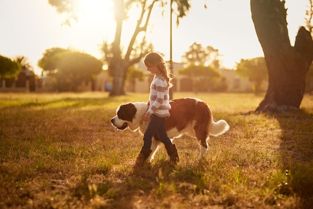 Waar zij gaat, gaat hij heen Shot van een schattig klein meisje dat met haar hond door een park loopt