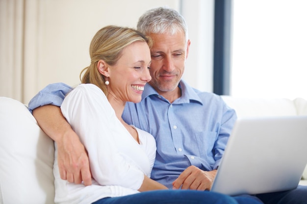 Waar zou je heen willen voor ons jubileum Een jong getrouwd stel samen op de bank met hun laptop