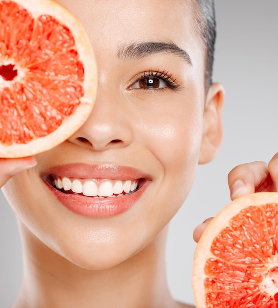 Foto waar zou mijn huid zijn zonder vitamine c studio-opname van een aantrekkelijke jonge vrouw die grapefruit tegen haar gezicht houdt tegen een grijze achtergrond