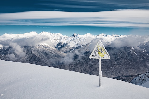 Waarschuwingsbord bedekt met sneeuw aan de rand van de skipiste in de bergen