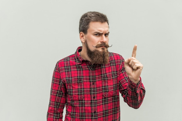 Waarschuwingsbord jonge volwassen zakenman met baard en stuursnor die naar camera kijkt met