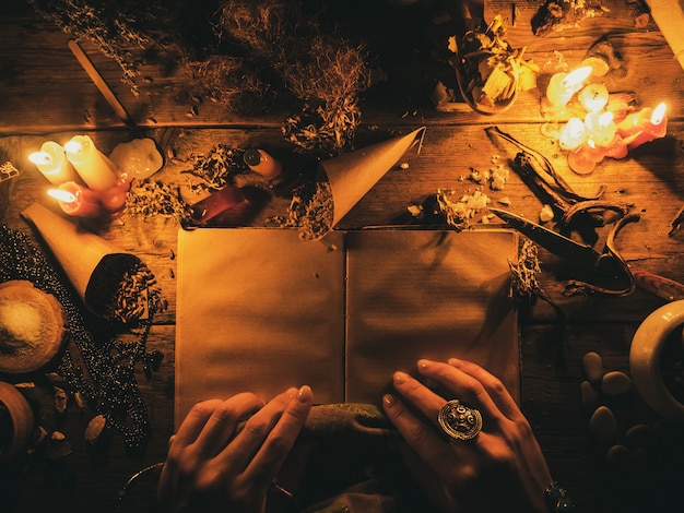 Foto waarzeggerij met behulp van oude boeken en van de droge afrikaanse kruiden. het licht van de kaarsen op de oude magische tafel. kenmerken van occultisme en magie.