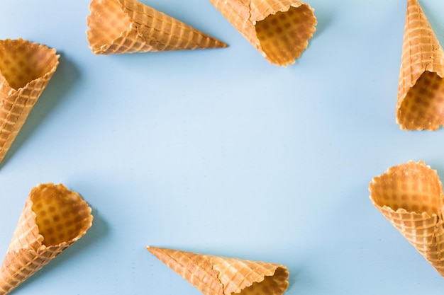 Wafel ijshoorntjes met bolletjes ijs op een blauwe achtergrond.