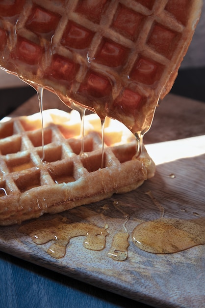 Foto wafel met honing die op houten tafel valt