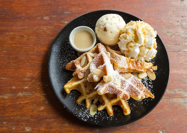 Wafel met roomijs op zwarte plaat.