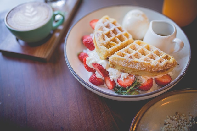 Foto wafel pannenkoek dessert met vanille-ijs verse aardbeien en honingsiroop