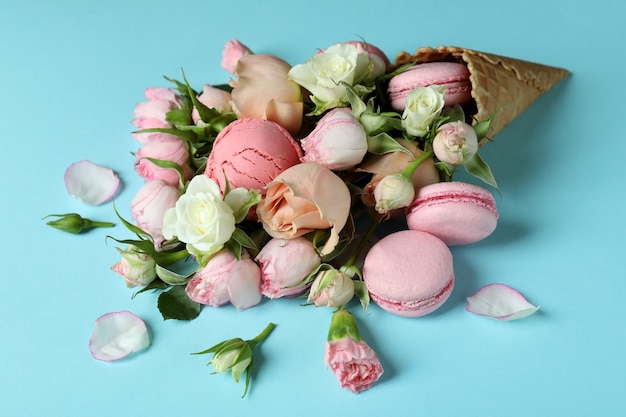 Wafelkegel met bloemen, roomijsballen en makarons op blauwe achtergrond