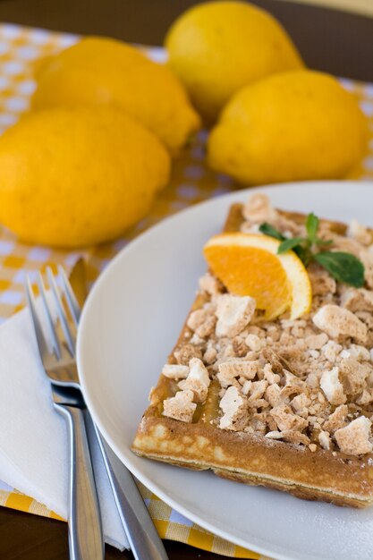 Wafels met meringue, citroenkrullen en stukjes sinaasappel als ontbijt