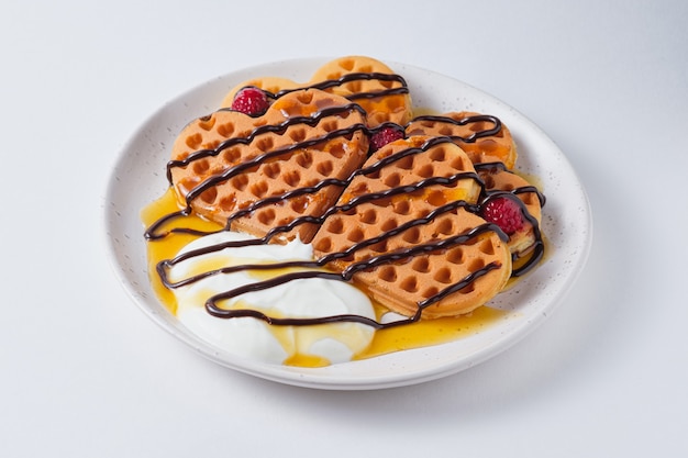 Wafels met yoghurt frambozen chocolade en perziksiroop Schotel op een wit bord