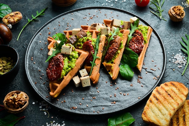 Wafelsandwiches met avocadopaté zongedroogde tomaten en tofu-kaas Het concept van dieetvoeding op een stenen achtergrond