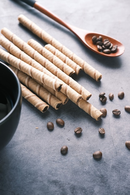 Wafer roll chocolate  coffee beans and coffee mug on table