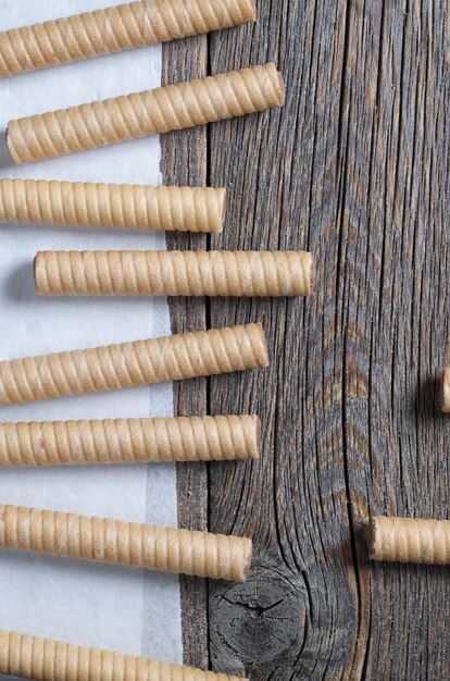 Wafer rolls with chocolate on old wooden background top view