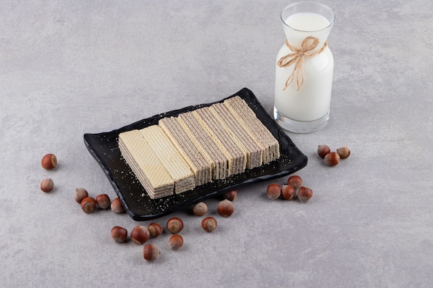 Wafer stack on plate and bottle of milk on grey background. 