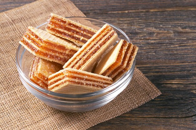 Wafers with apricot layers in glass bowl on rustic wooden table