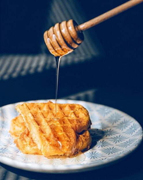 Wafers with honey on a wooden table, in the rays of the morning sun.