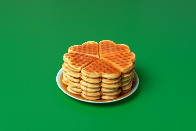 Foto waffels met esdoornstroop op een bord op een groene achtergrond