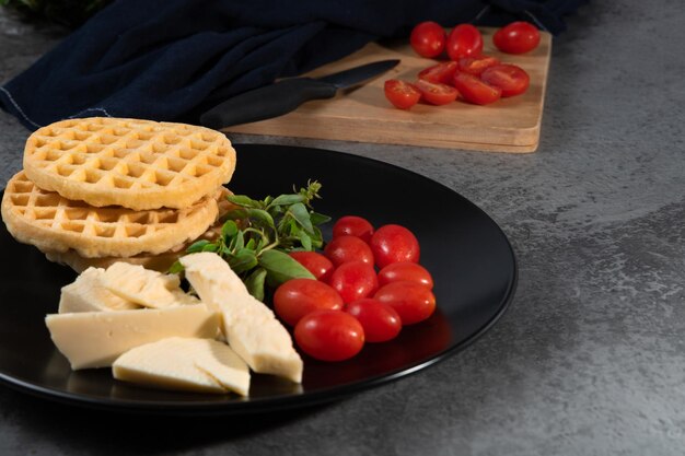 Waffle cheese basil and tomatoes on black plate Selective focus