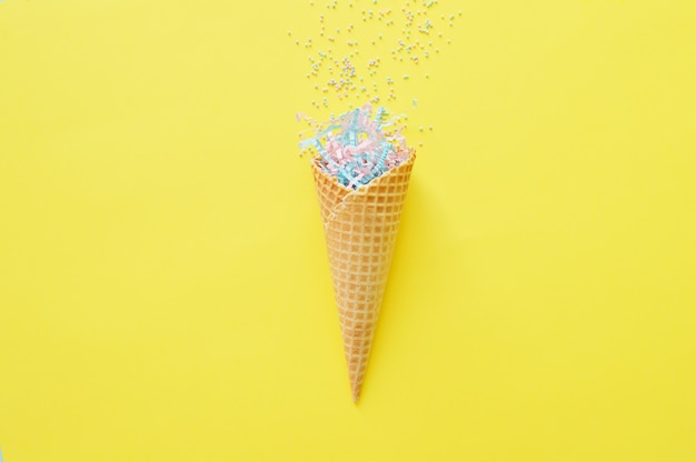 Waffle cone on a bright yellow background with festive tinsel