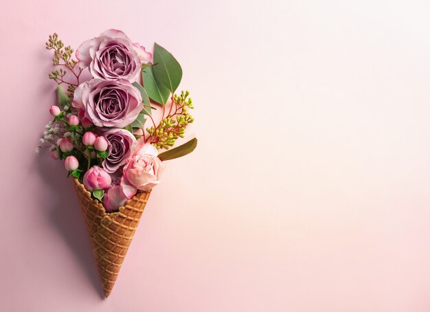 Waffle cone with composition of flowers and branches on pink