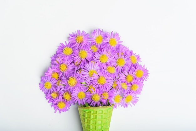 Cono di cialda con fiori aster alpino su uno sfondo bianco concetto 8 marzo, san valentino.