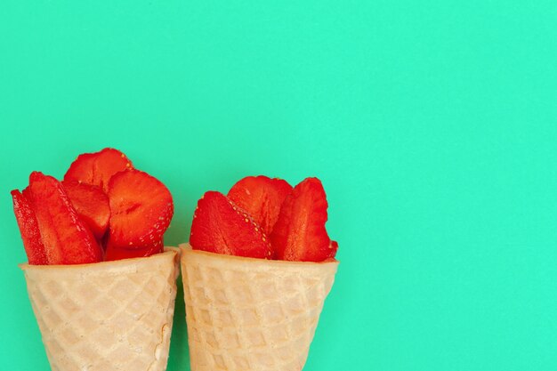 Waffle cone with fresh strawberries on vibrant background