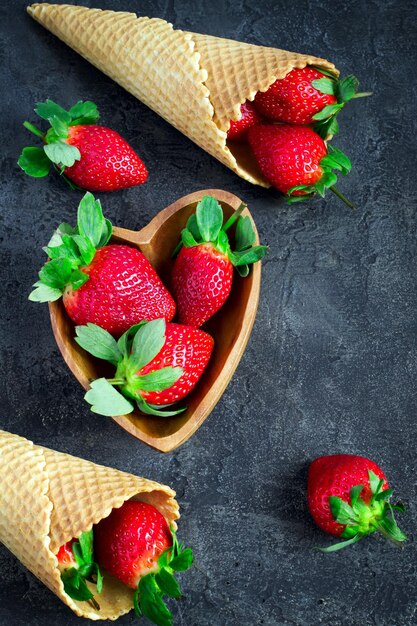 Waffle cone with ripe strawberries from a composition on a dark background. Top view with copy space