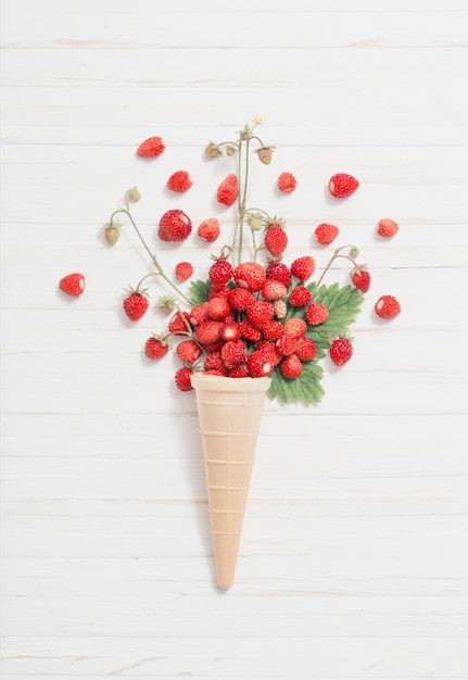 Waffle cone with strawberries on wooden background